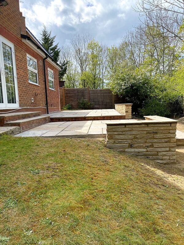 Paved patio with brick steps and a natural stone garden wall with coping stones